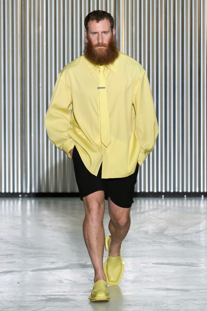 A relaxed yellow long-sleeve collared shirt paired with black shorts.
