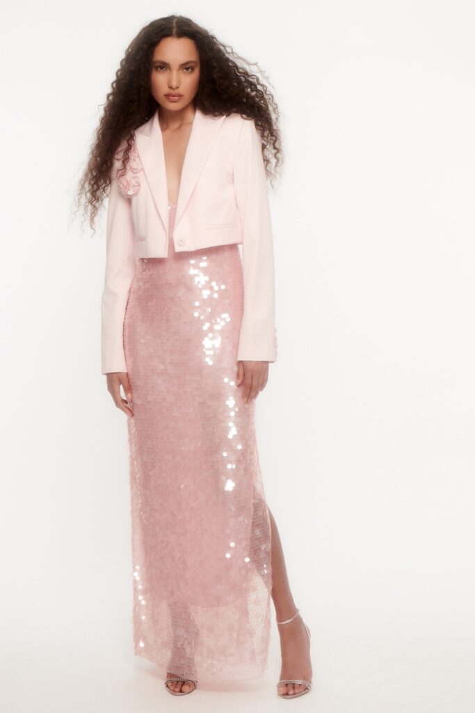 A fitted pink sequin dress layered with a cropped jacket featuring a V-neckline and a side slit.