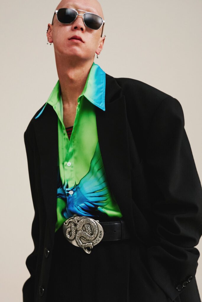 A relaxed black jacket paired with a long-sleeve printed shirt featuring vibrant colors.