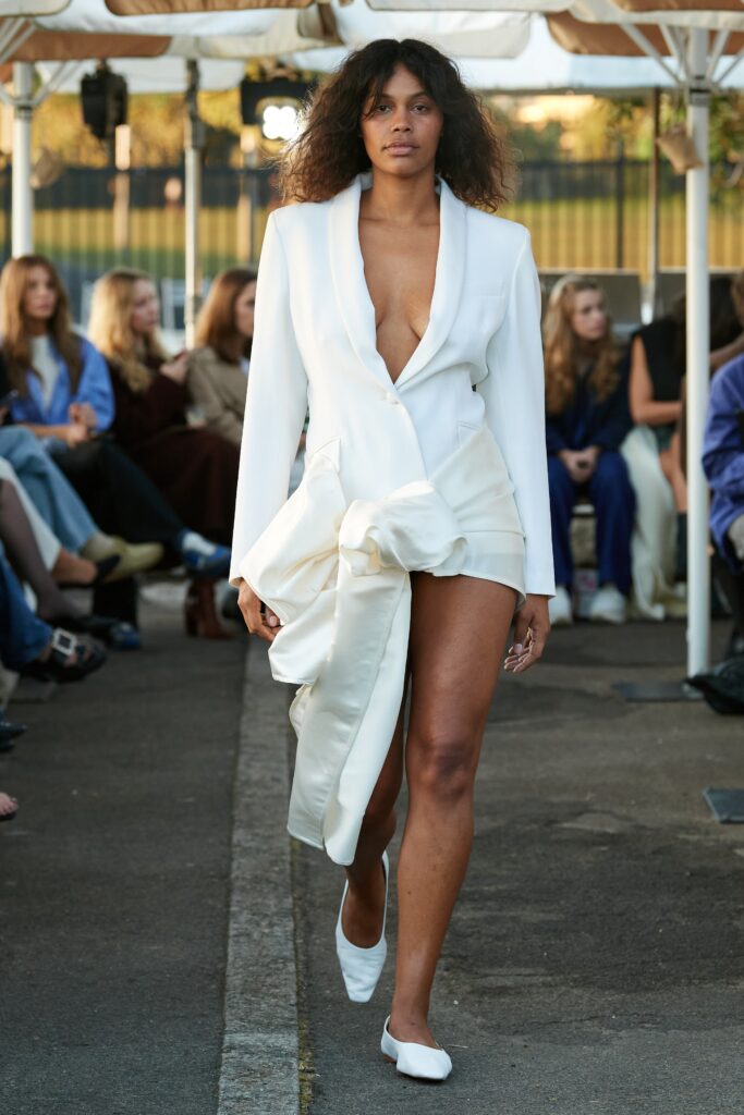 A fitted white silk sleeveless dress with a V-neckline and asymmetric design.
