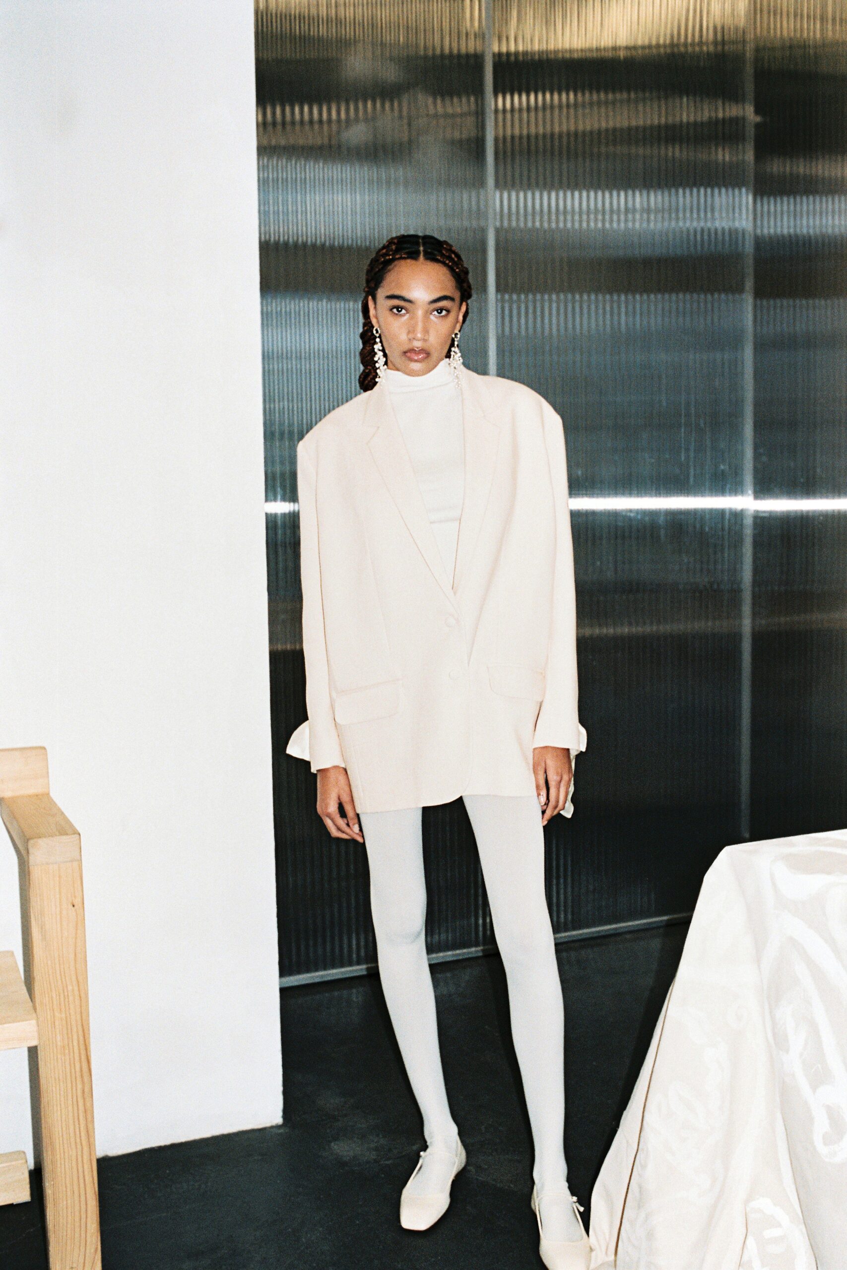 A fitted white blazer paired with a long-sleeve top, featuring a structured design.