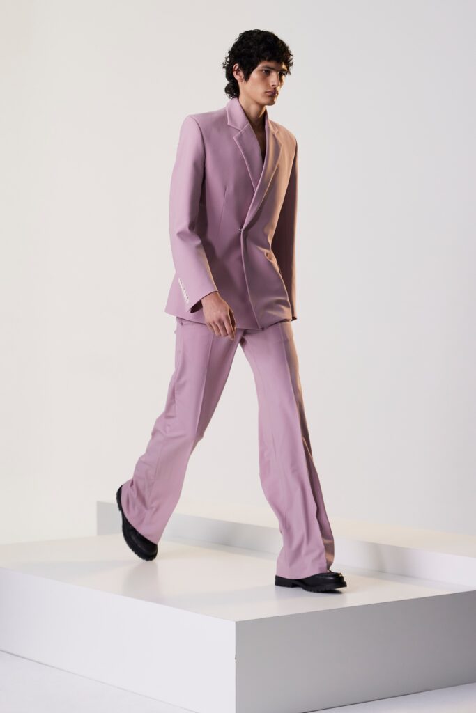 A tailored pink suit featuring long sleeves and a flared silhouette.