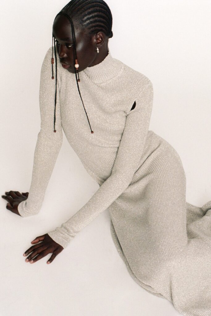 A fitted gray knit dress with long sleeves, a high neckline, and a stylish slit.