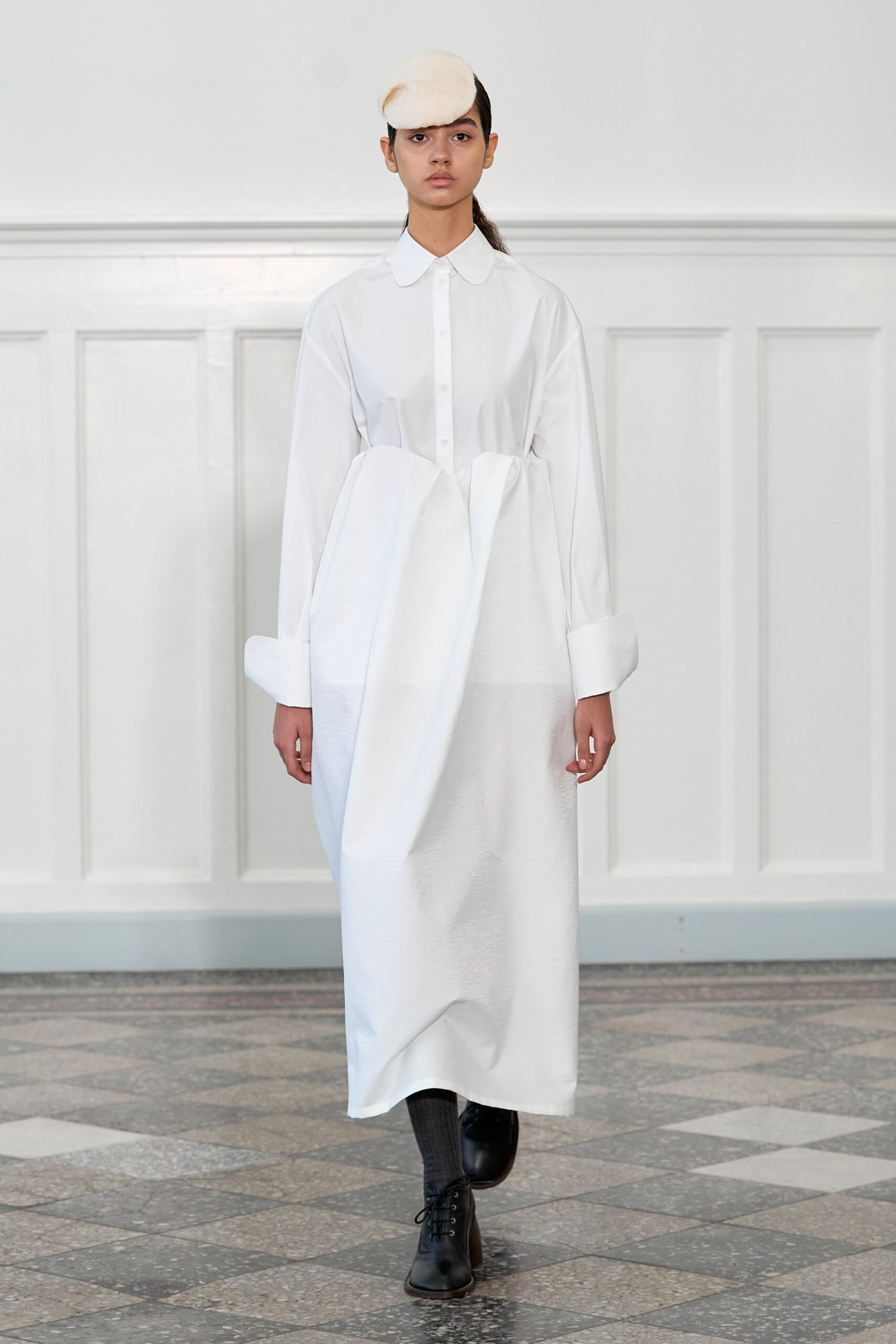 A relaxed white long-sleeve dress with a collared neckline and asymmetric design.