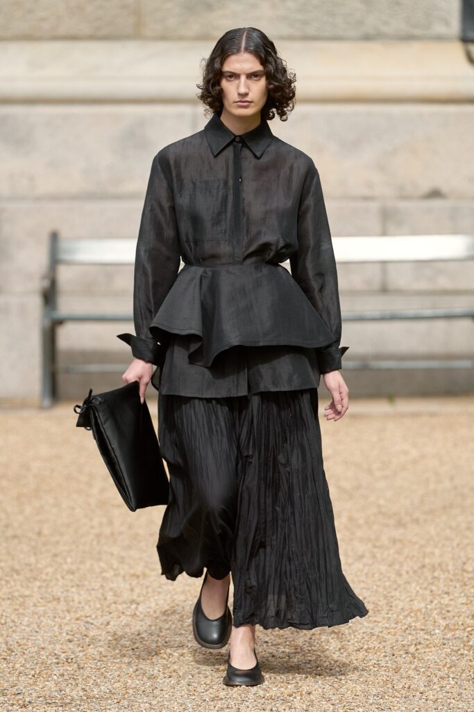 A fitted black silk dress with long sleeves and a pleated design detail.