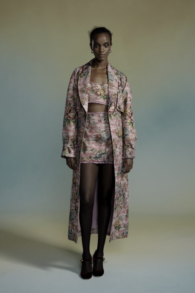 A fitted pink floral silk coat layered over a matching skirt, showcasing a stylish ensemble.