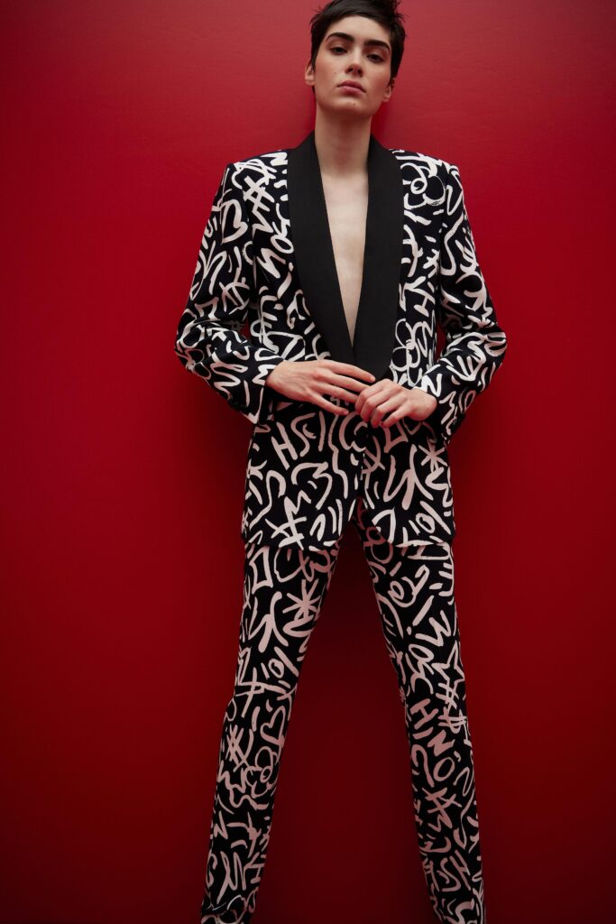 This fitted suit features a striking black and white print that creates a dynamic visual impact. The deep V-neckline and long sleeves enhance the structured silhouette, while the bold pattern adds an element of artistic flair, making it a standout choice for modern fashion.