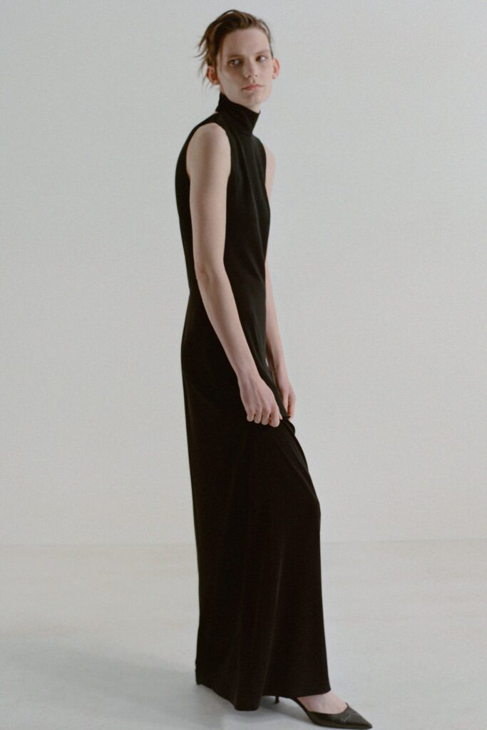 A fitted black sleeveless dress with a high-neck design and straight silhouette.