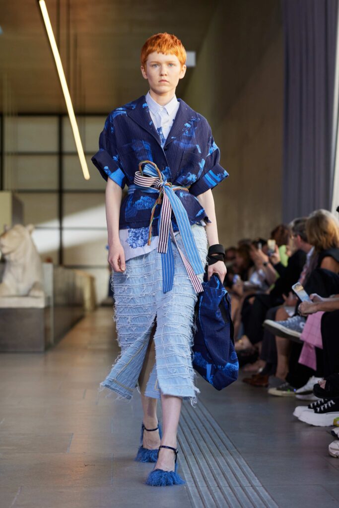 An oversized blue jacket layered over a white shirt paired with denim pants.