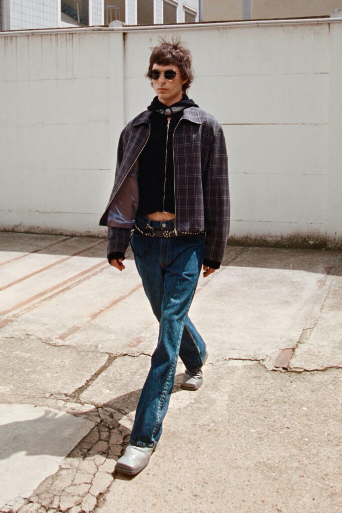 A relaxed black jacket with long sleeves and a collared design paired with straight-leg blue pants.