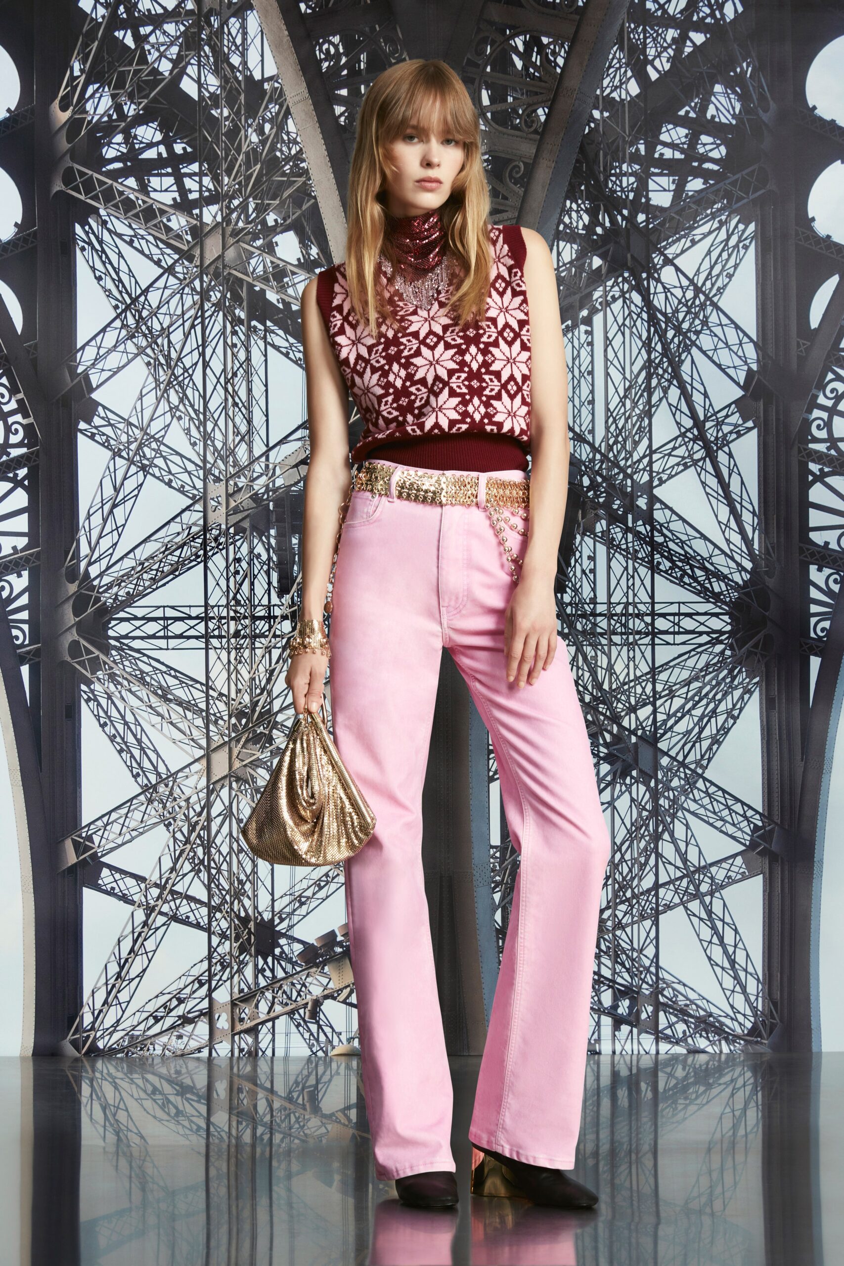 A fitted pink printed sleeveless top paired with flared burgundy pants.
