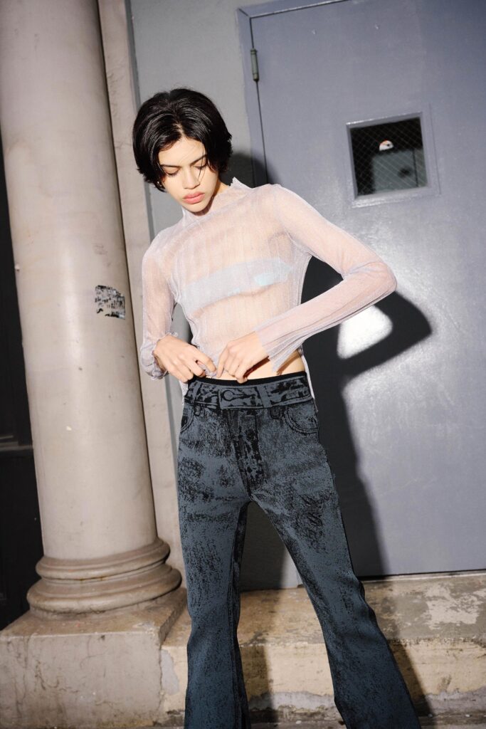 A fitted white long-sleeve top with a high-neck paired with flared black pants.