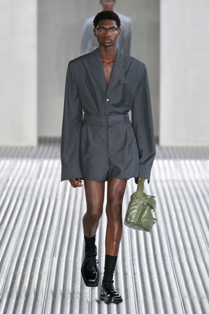A fitted gray jacket with long sleeves and a V-neck, paired with matching shorts in an asymmetric style.