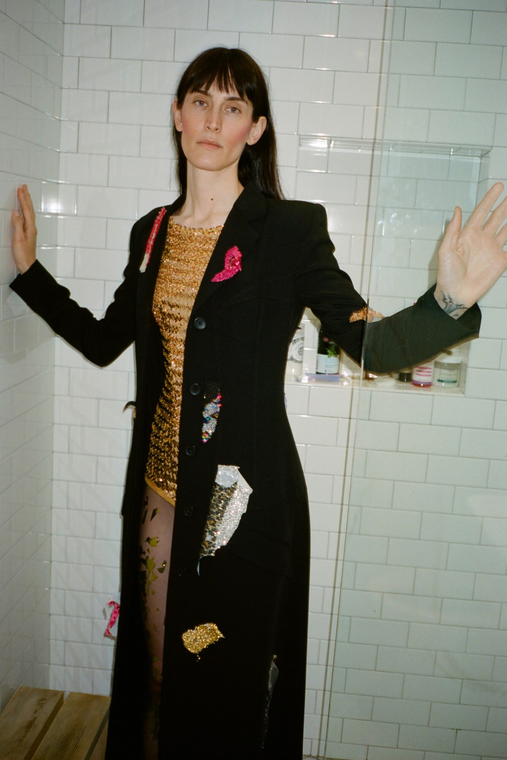 A fitted black coat dress featuring long sleeves, a V-neckline, and intricate embroidery.