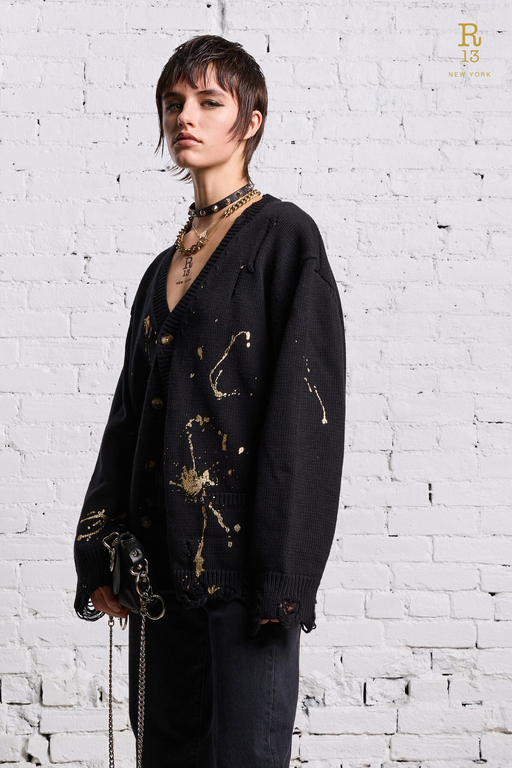 An oversized black sweater with a V-neck and printed design paired with black pants.