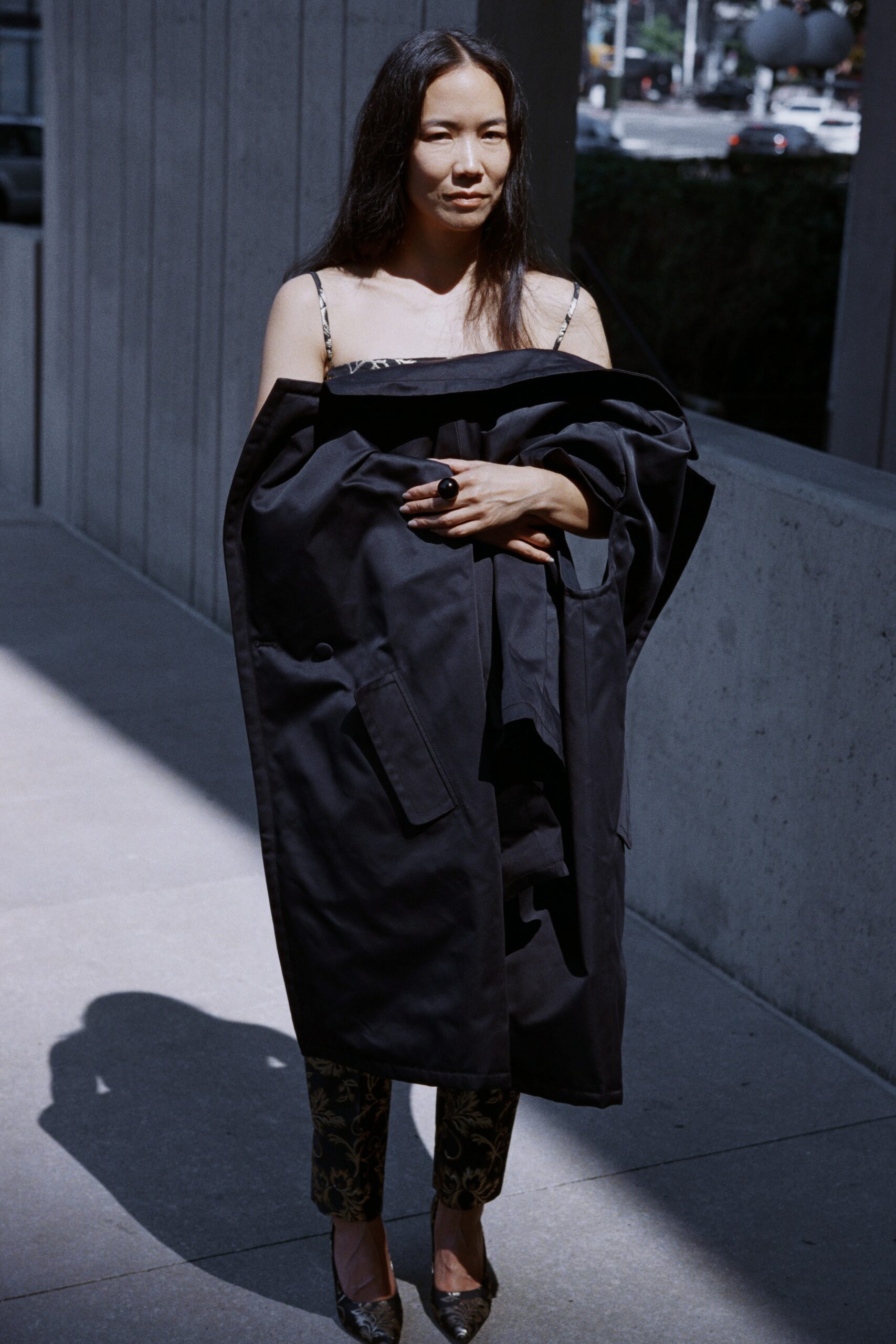 A fitted black coat worn over patterned pants, featuring a collared design.