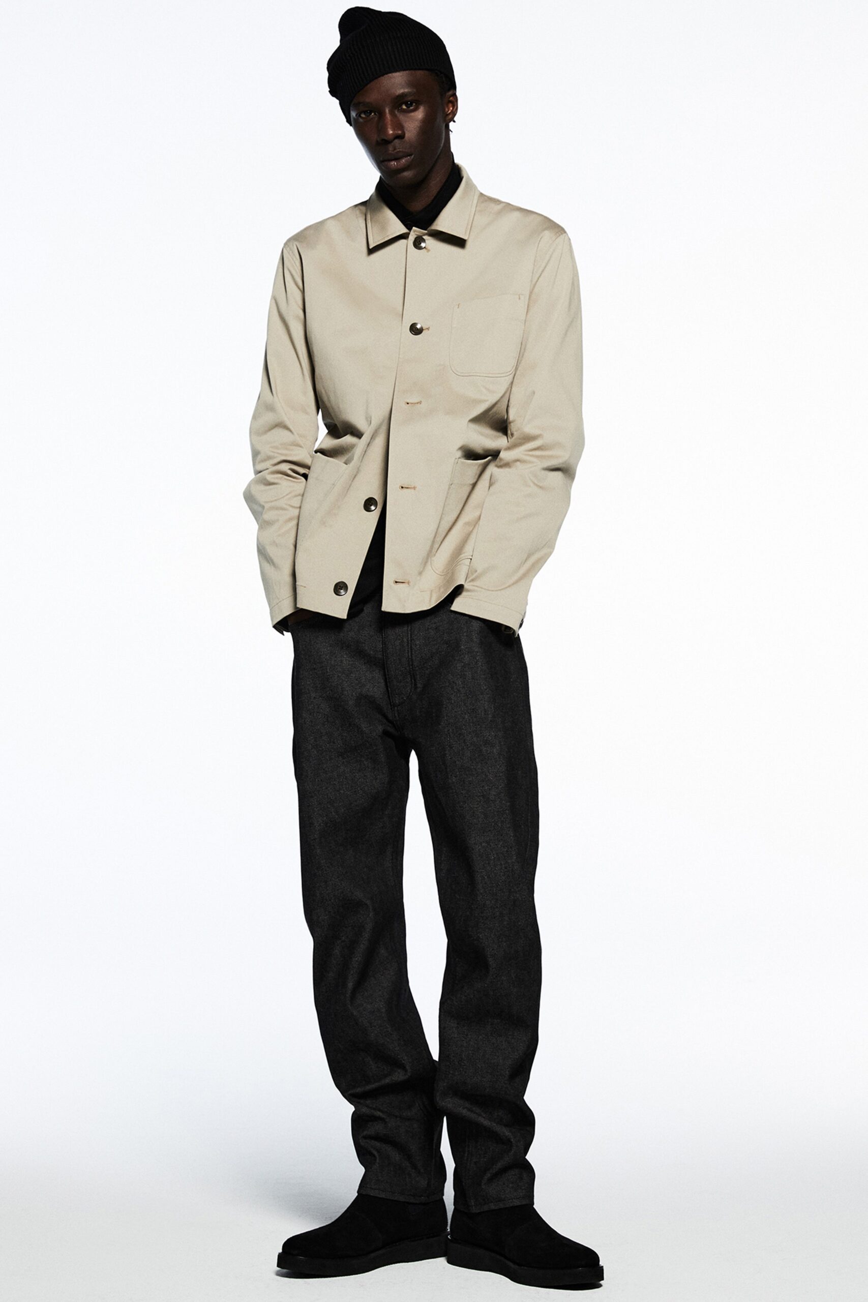 A relaxed-fit beige jacket with long sleeves and collared neck paired with straight-leg black pants.