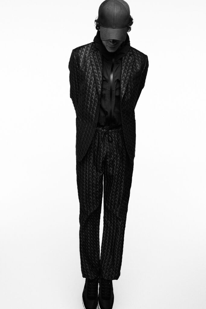A fitted black suit with a textured finish, featuring long sleeves and a collared shirt.