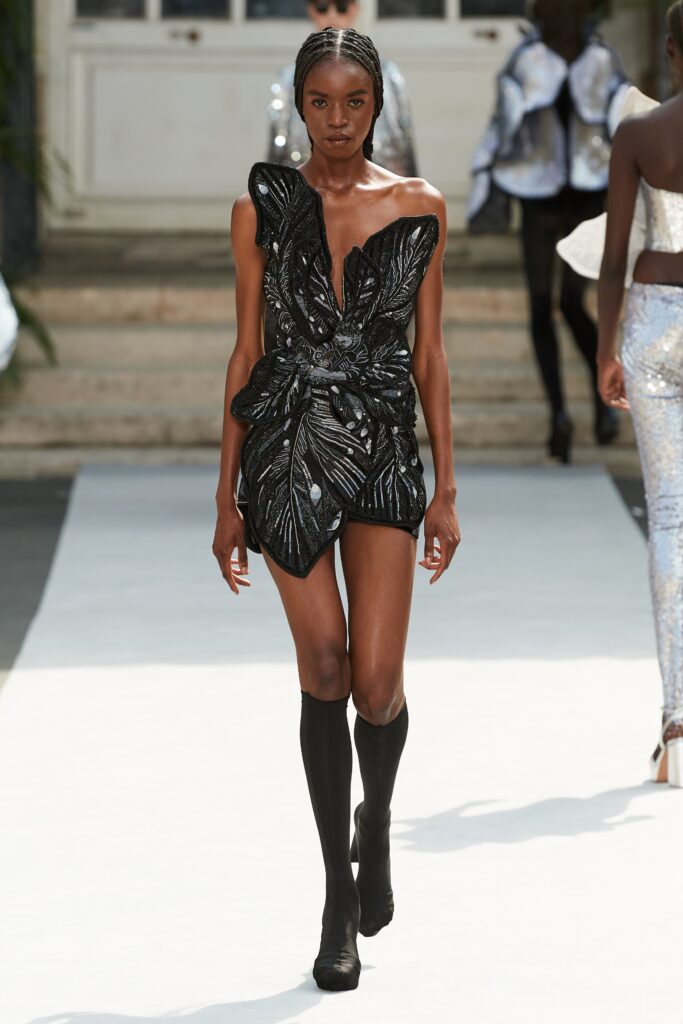 A fitted black silk sleeveless dress with a V-neckline and embroidered detailing.