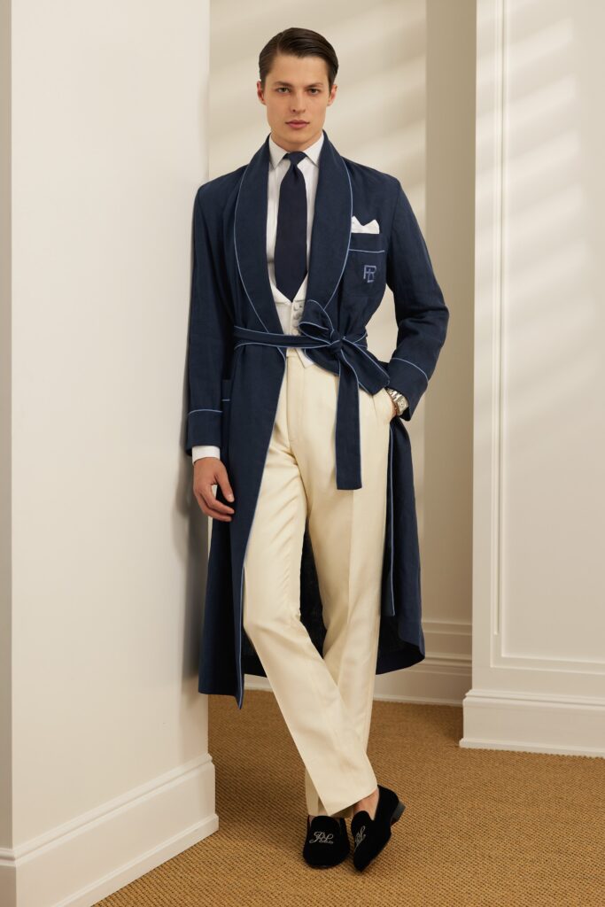A tailored blue cotton coat with long sleeves and a collared neckline paired with white pants.