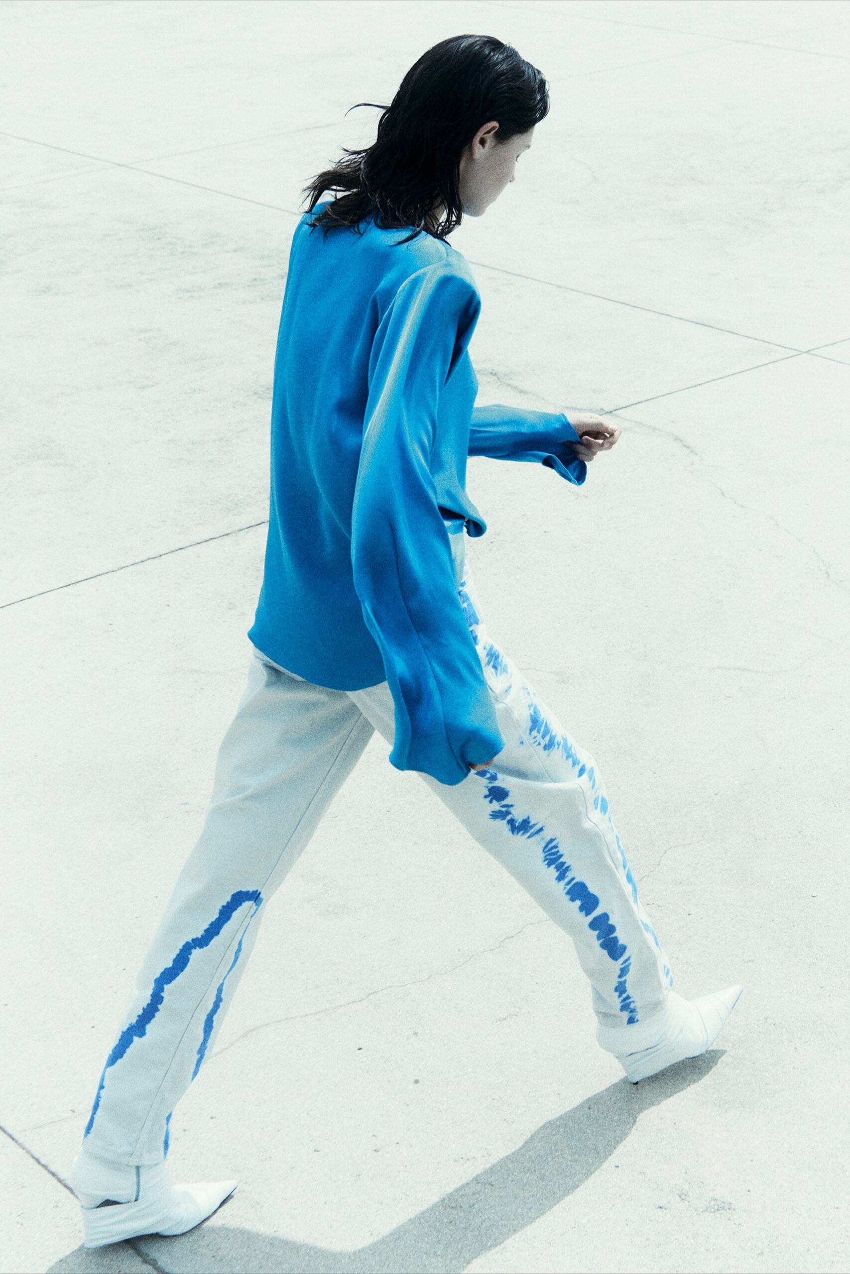 A relaxed blue long-sleeve top paired with white asymmetric pants.