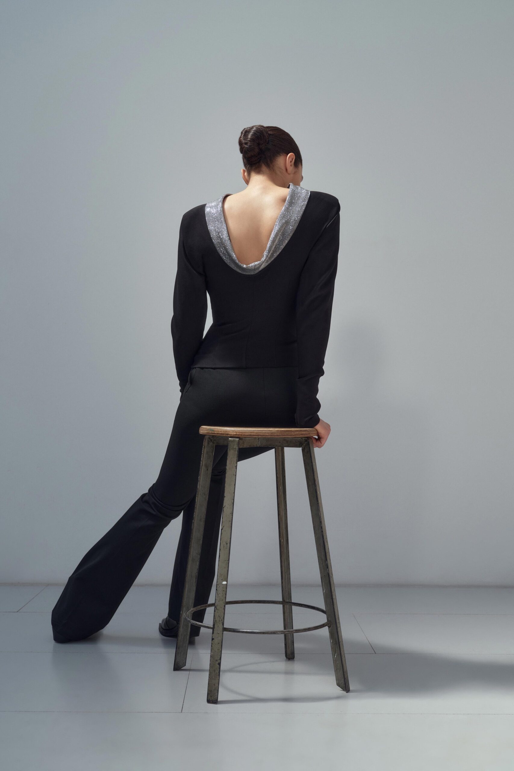 A fitted black jacket with a V-neckline paired with sleek black pants featuring an asymmetric design.