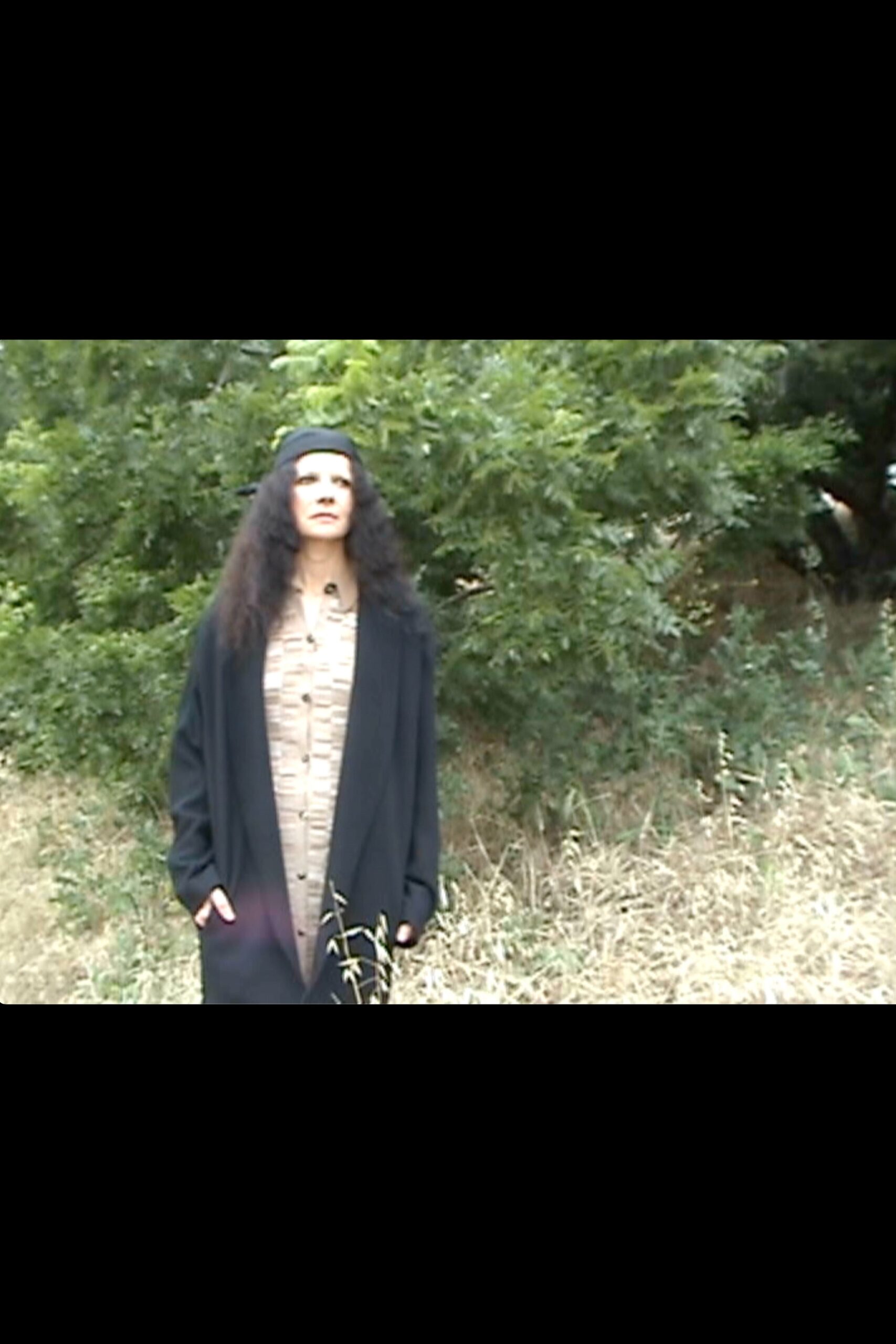A relaxed black coat dress with long sleeves and a collared design, featuring button details.
