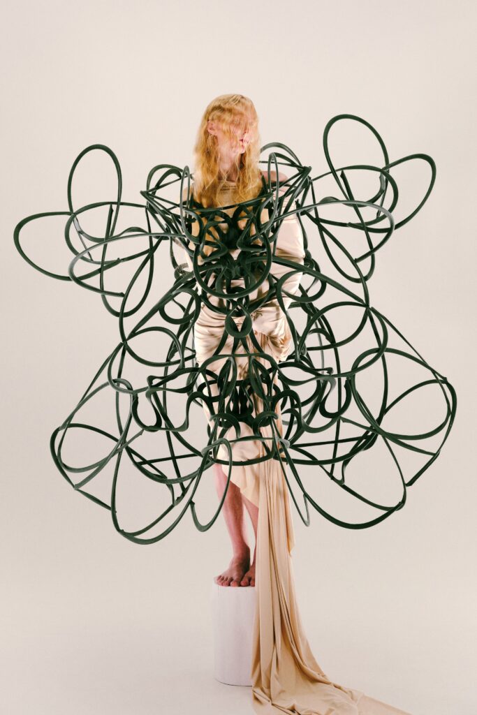 An asymmetric beige silk dress with long sleeves and unique sculptural detailing.