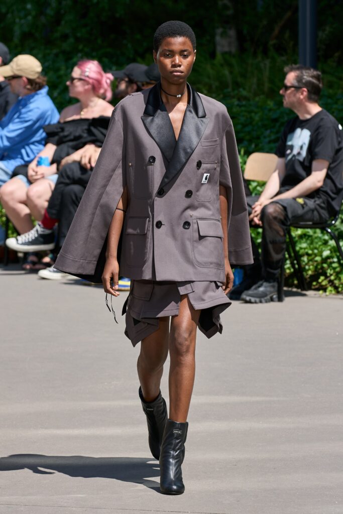 A fitted gray sleeveless dress with a collared coat and asymmetric layered design.