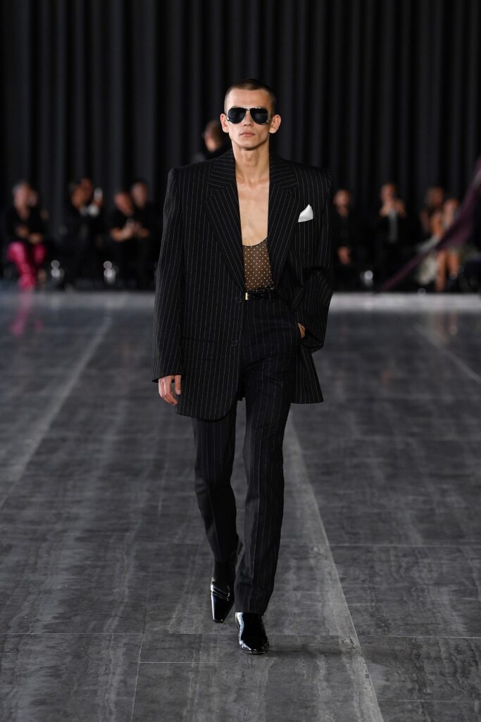 A tailored black striped suit with long sleeves and a collared shirt.