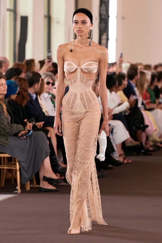 A fitted beige lace sleeveless jumpsuit with a V-neckline and sheer detailing.