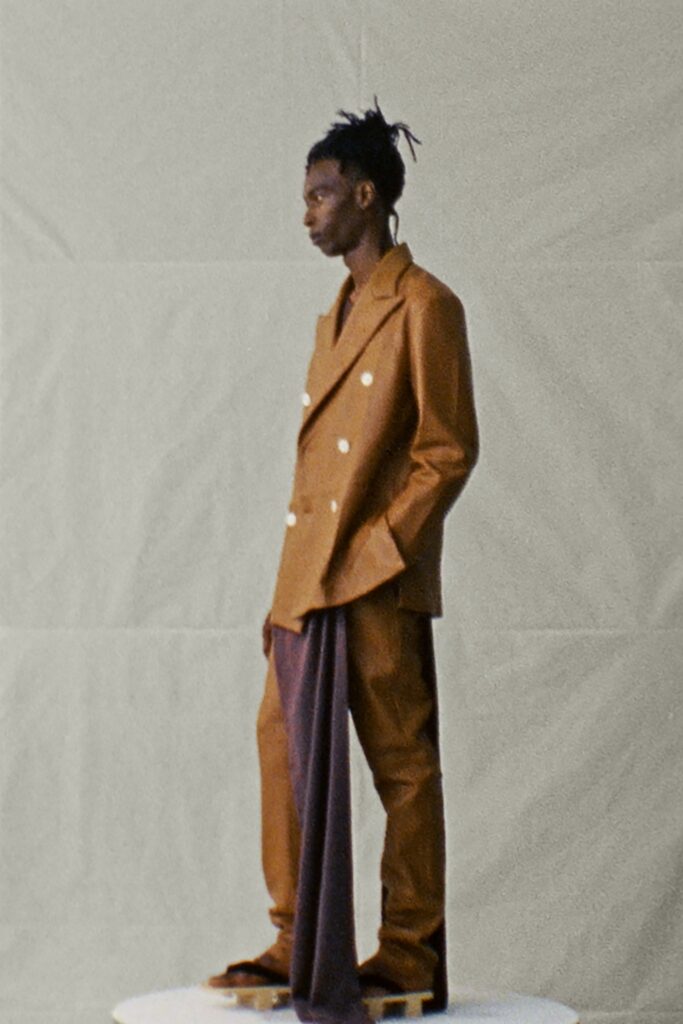 A tailored brown suit with long sleeves, a collared design, and asymmetric detailing.