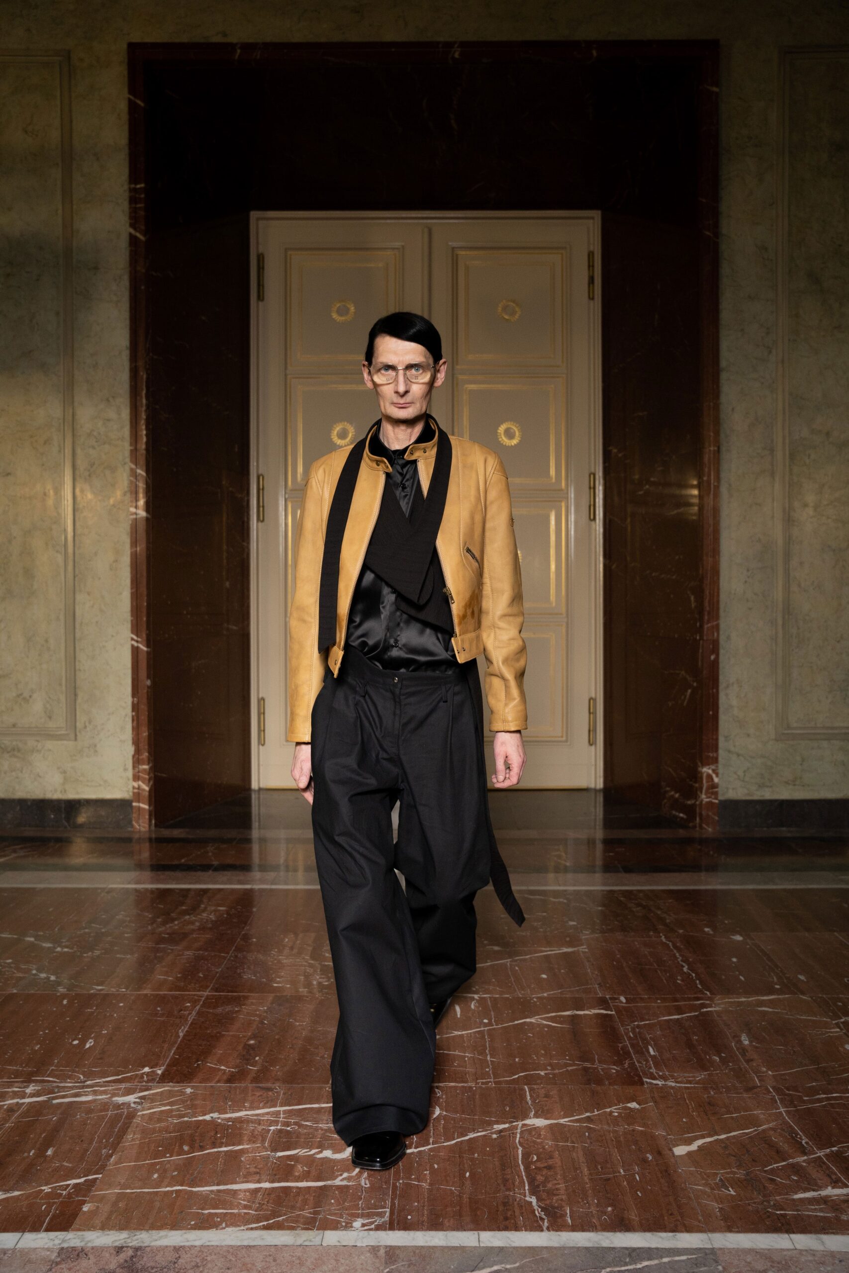 A relaxed brown leather jacket paired with black wide-leg pants featuring a collared design.