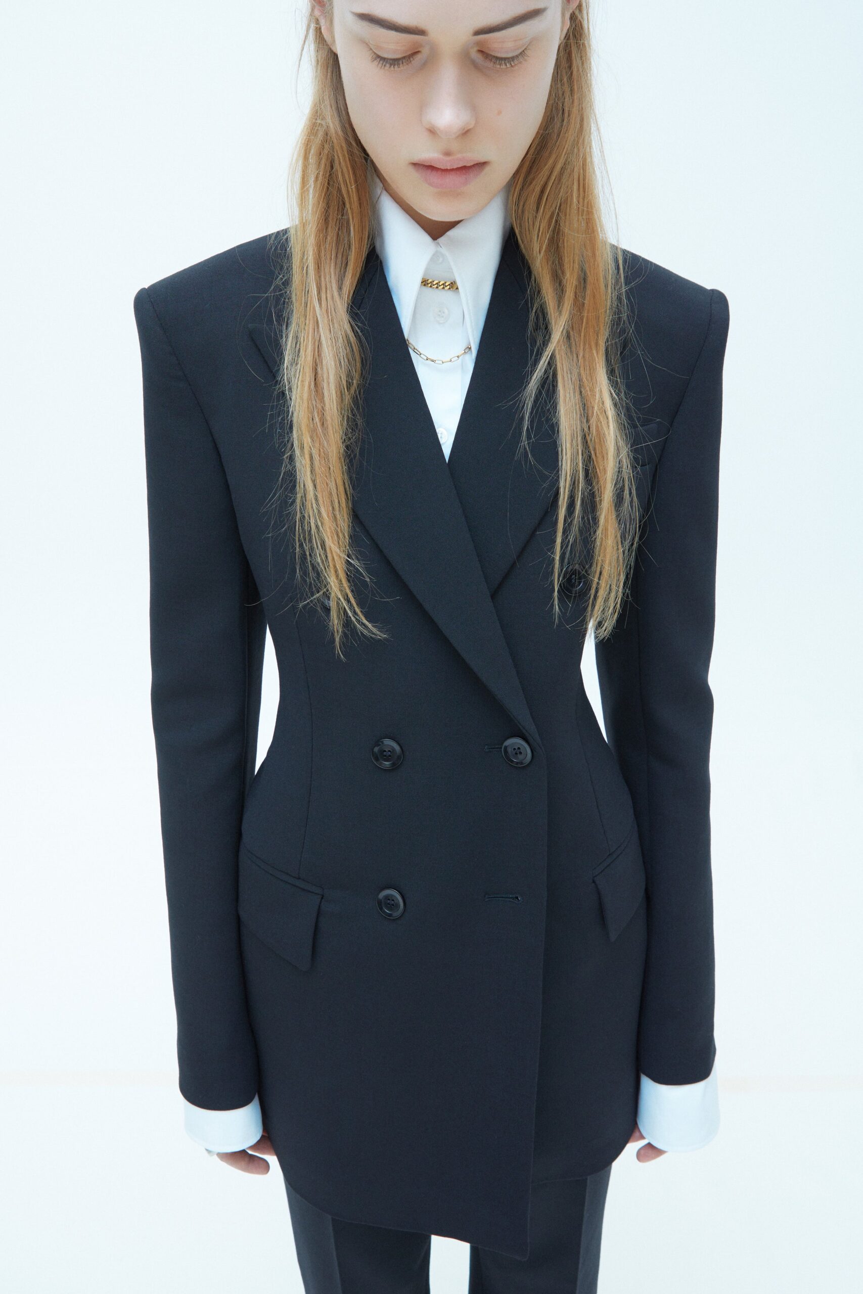 A tailored black wool double-breasted blazer with long sleeves and a collared design.