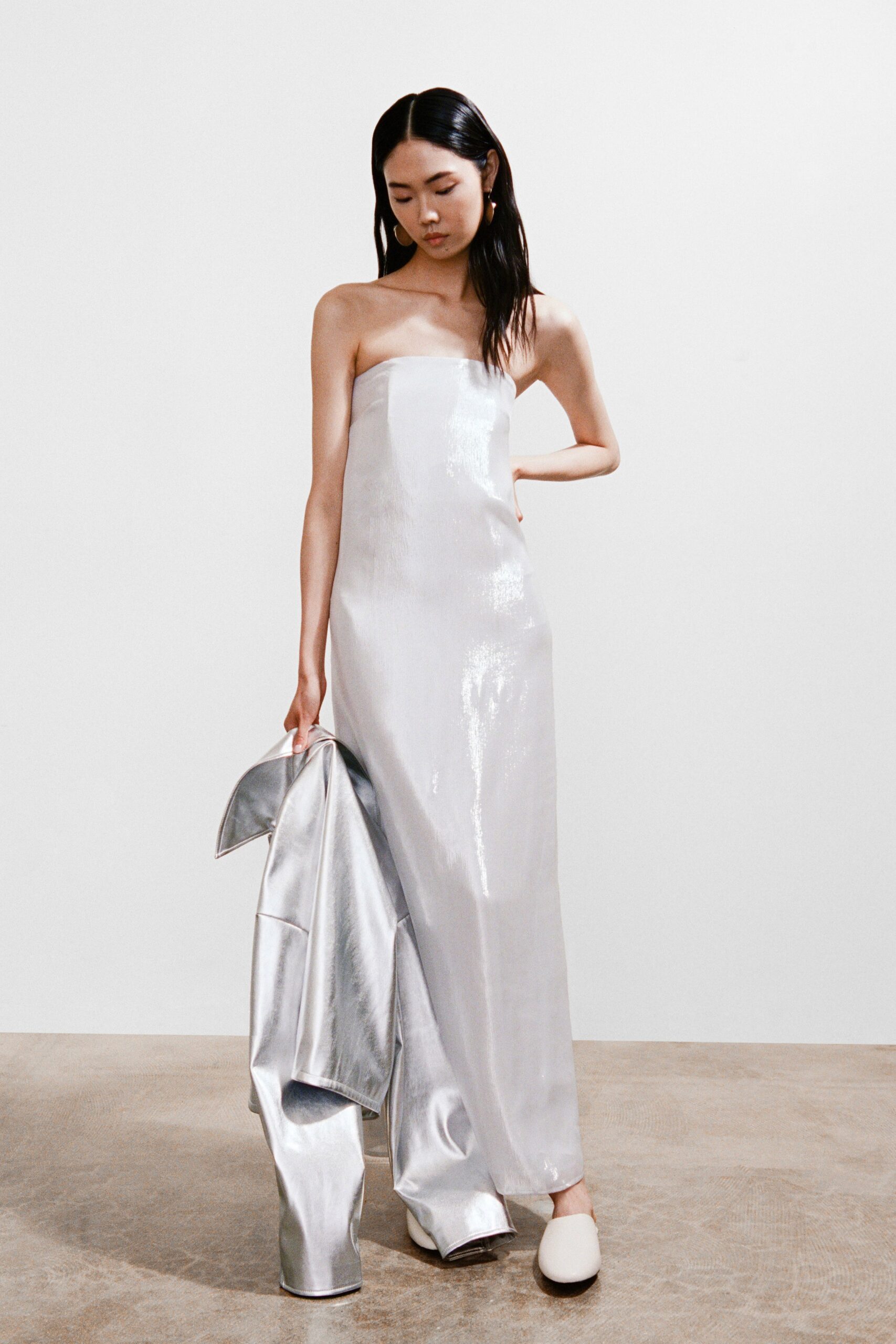 A fitted silver silk strapless dress with a maxi silhouette.