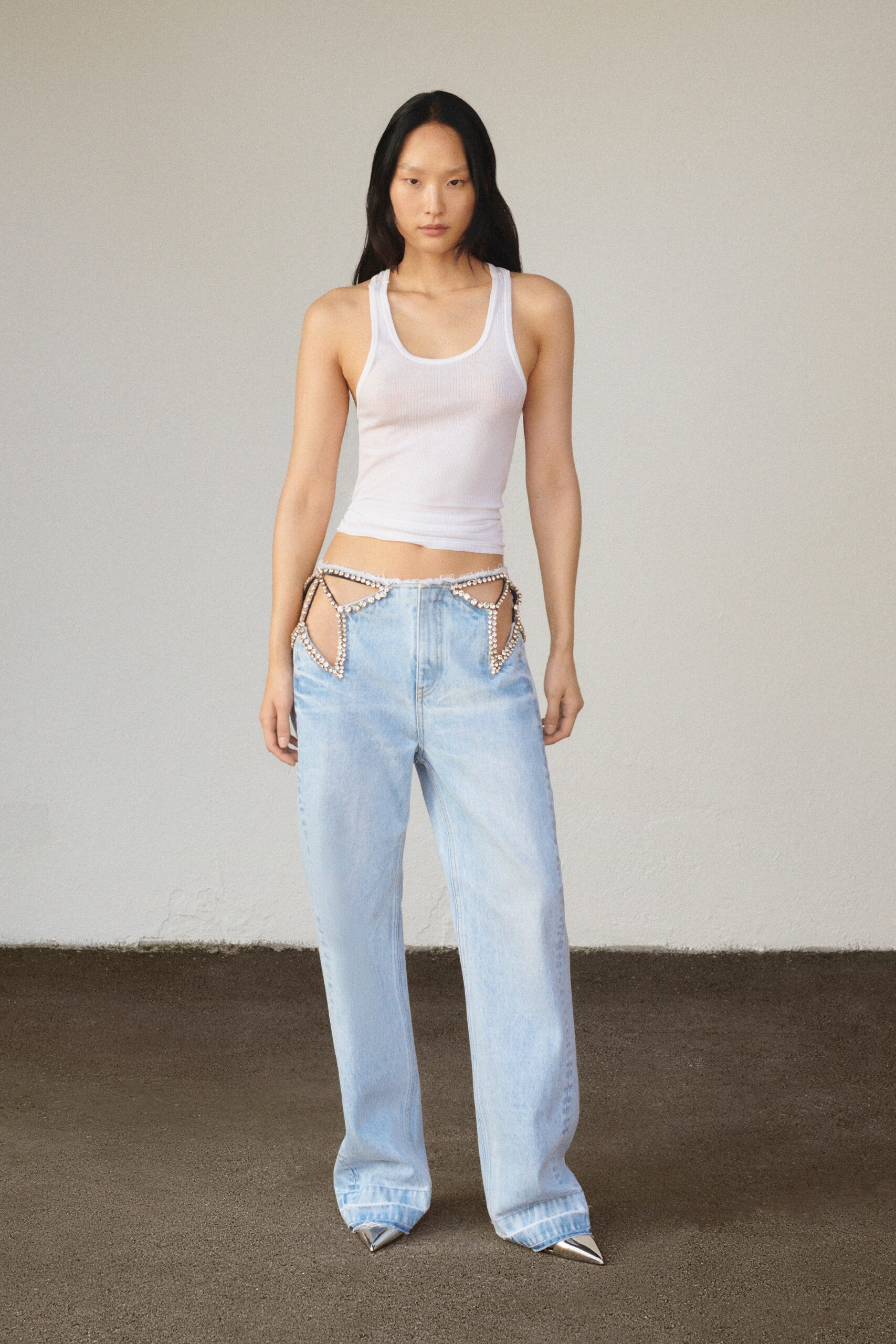 A fitted white sleeveless tank-top paired with high-waisted blue straight-leg pants.