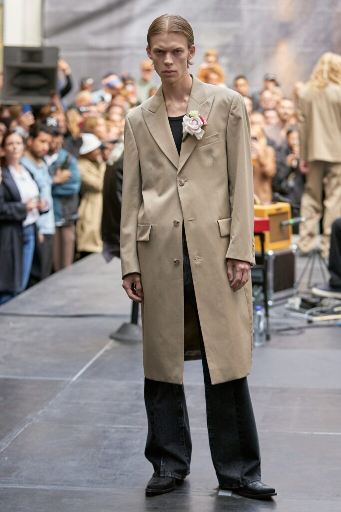A relaxed beige coat paired with black pants featuring a collared design and buttoned details.