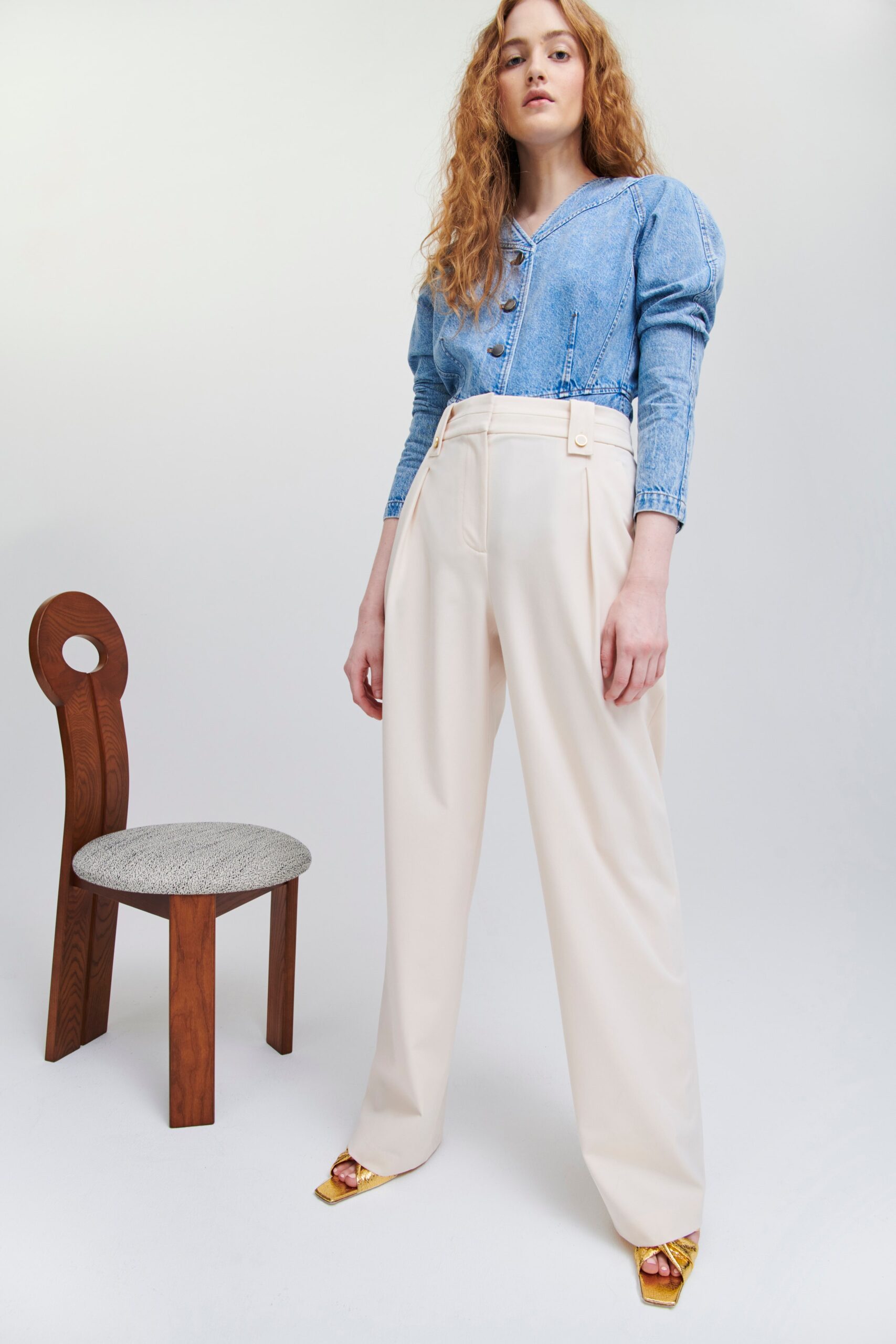 A relaxed blue denim blouse with a collared neckline paired with cream wide-leg pants.