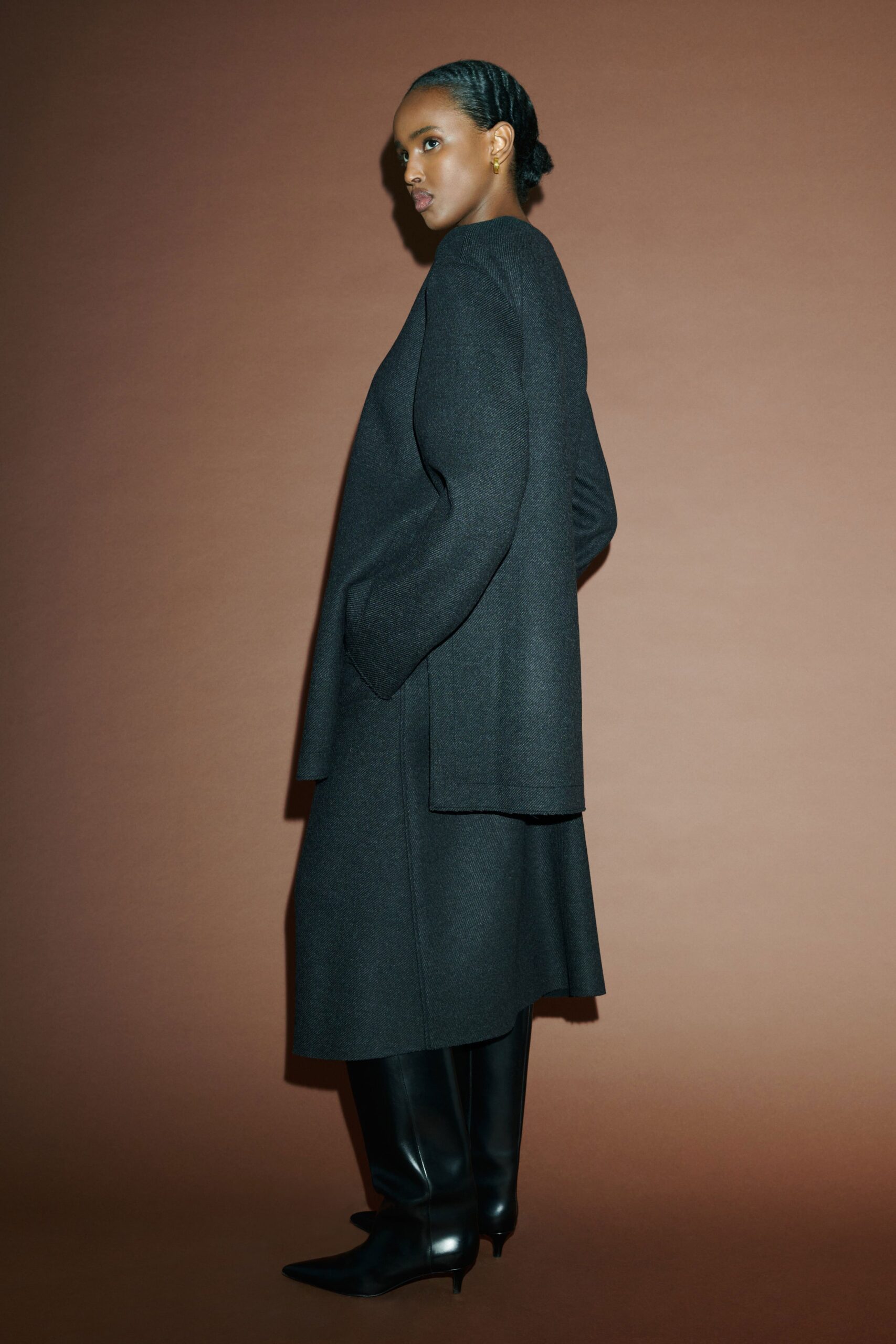 A relaxed black wool coat dress with long sleeves and an asymmetric design.