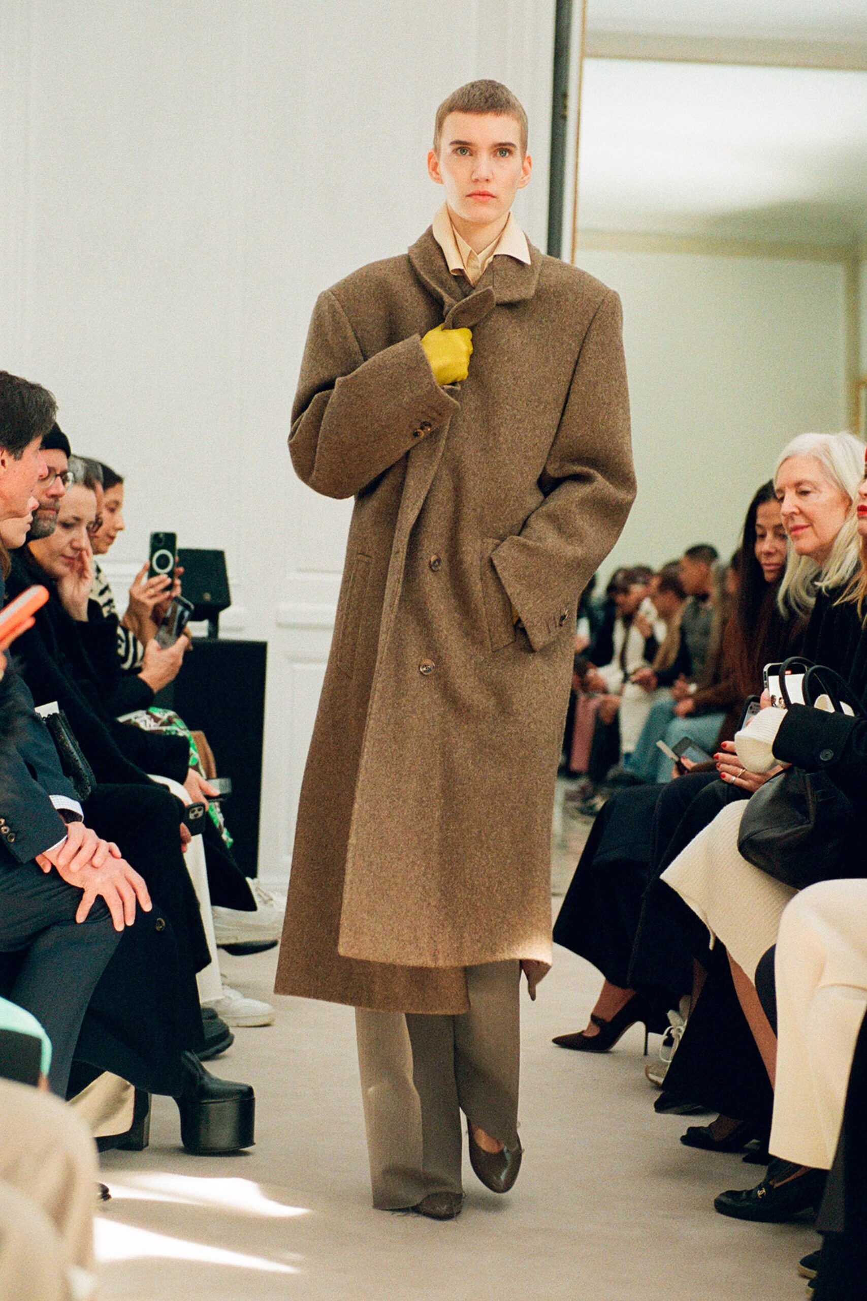 A relaxed brown wool coat with a collared neckline and buttoned detail, paired with beige pants.