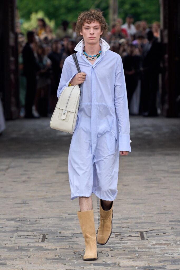 A relaxed blue cotton jumpsuit with long sleeves and a collared neckline, featuring button details.