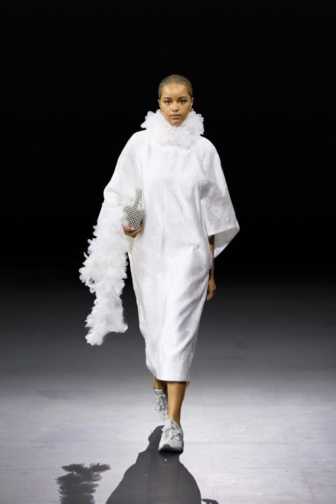 An asymmetric white silk sleeveless dress featuring a dramatic ruffled detail.