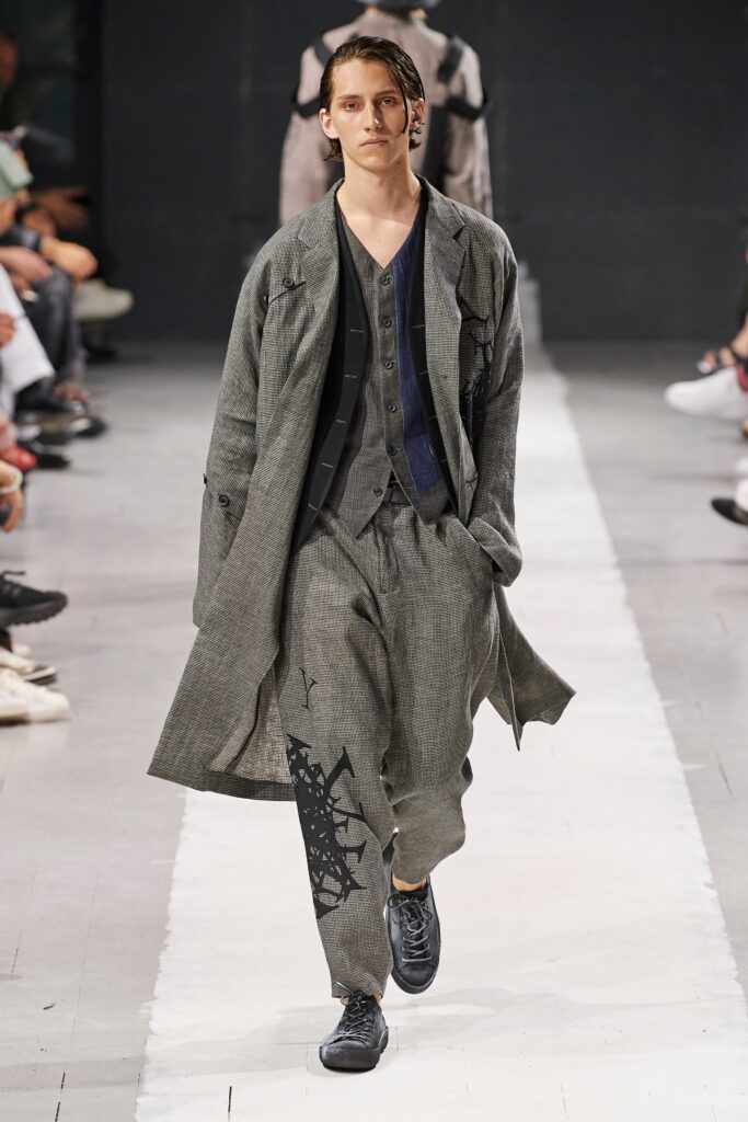 A relaxed gray cotton coat with long sleeves and layered buttoned details, paired with matching pants.
