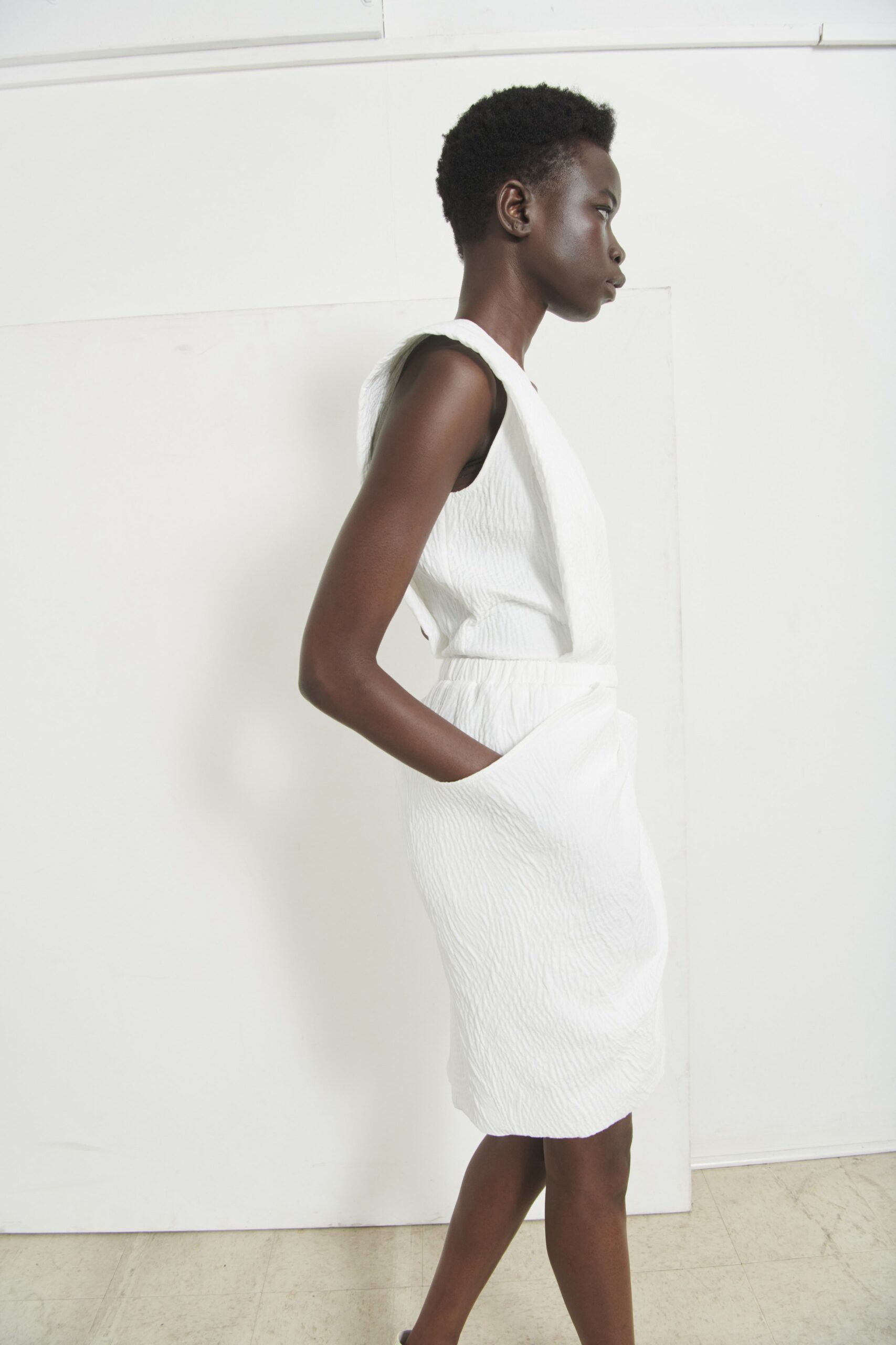 A fitted white sleeveless dress with a V-neckline and straight silhouette.