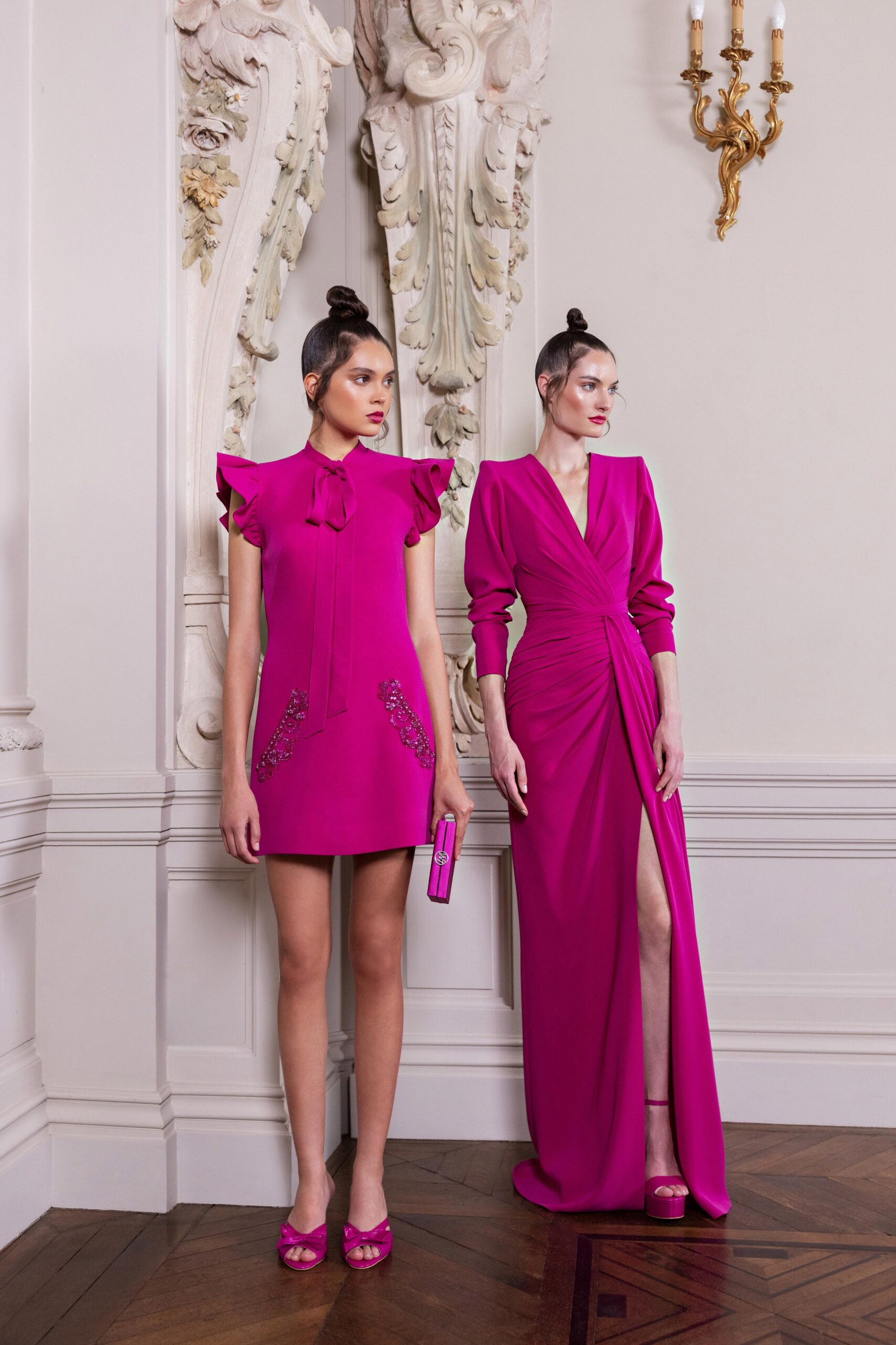 A fitted pink silk dress with a V-neckline, long sleeves, and a stylish slit.