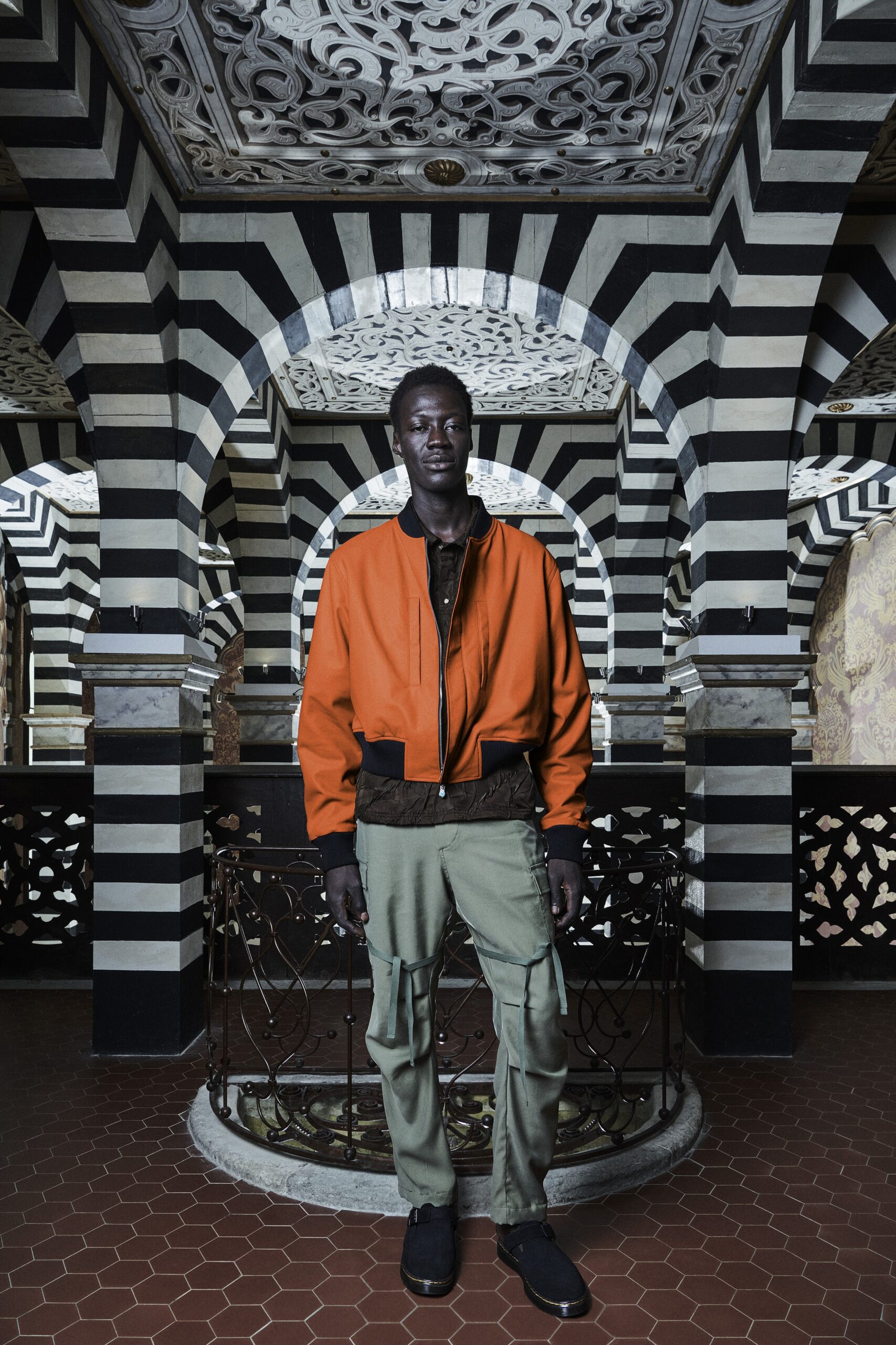 A relaxed fit orange cotton jacket paired with green pants featuring a zippered detail.