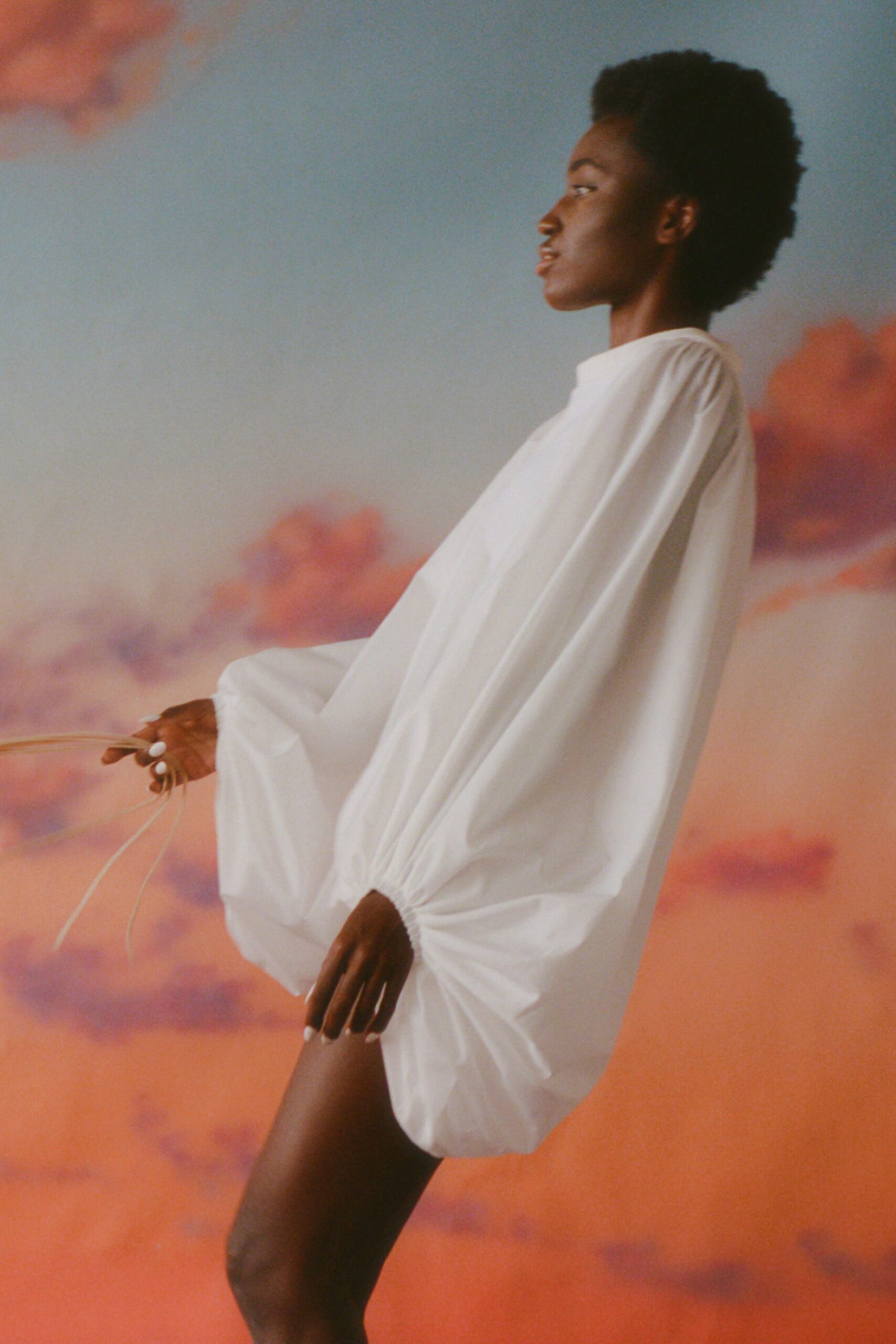 This relaxed dress features a high-neck design and voluminous long sleeves that create an intriguing silhouette. The asymmetric hemline adds a modern twist, allowing for dynamic movement and a striking visual impact.