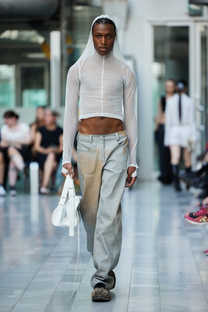 A fitted white mesh long-sleeve top paired with gray denim pants for a contemporary look.