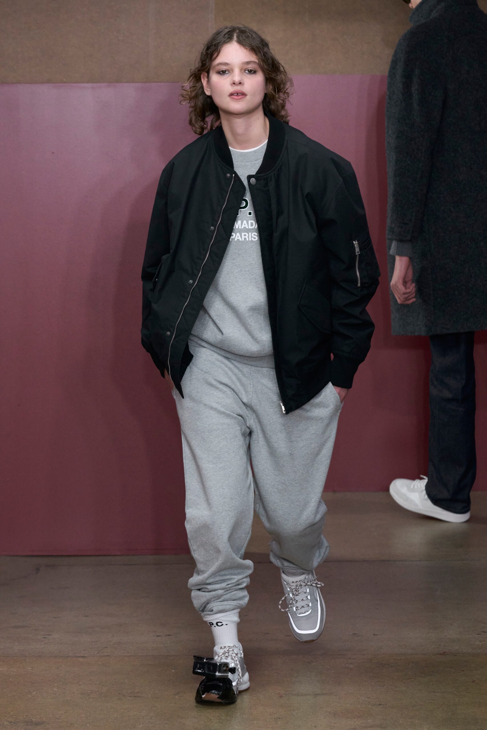 A relaxed black hooded jacket paired with gray cotton pants, featuring a zippered detail.