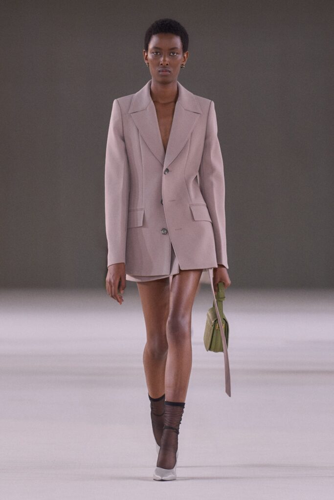A fitted beige blazer dress with a collared neckline and asymmetric design detail.